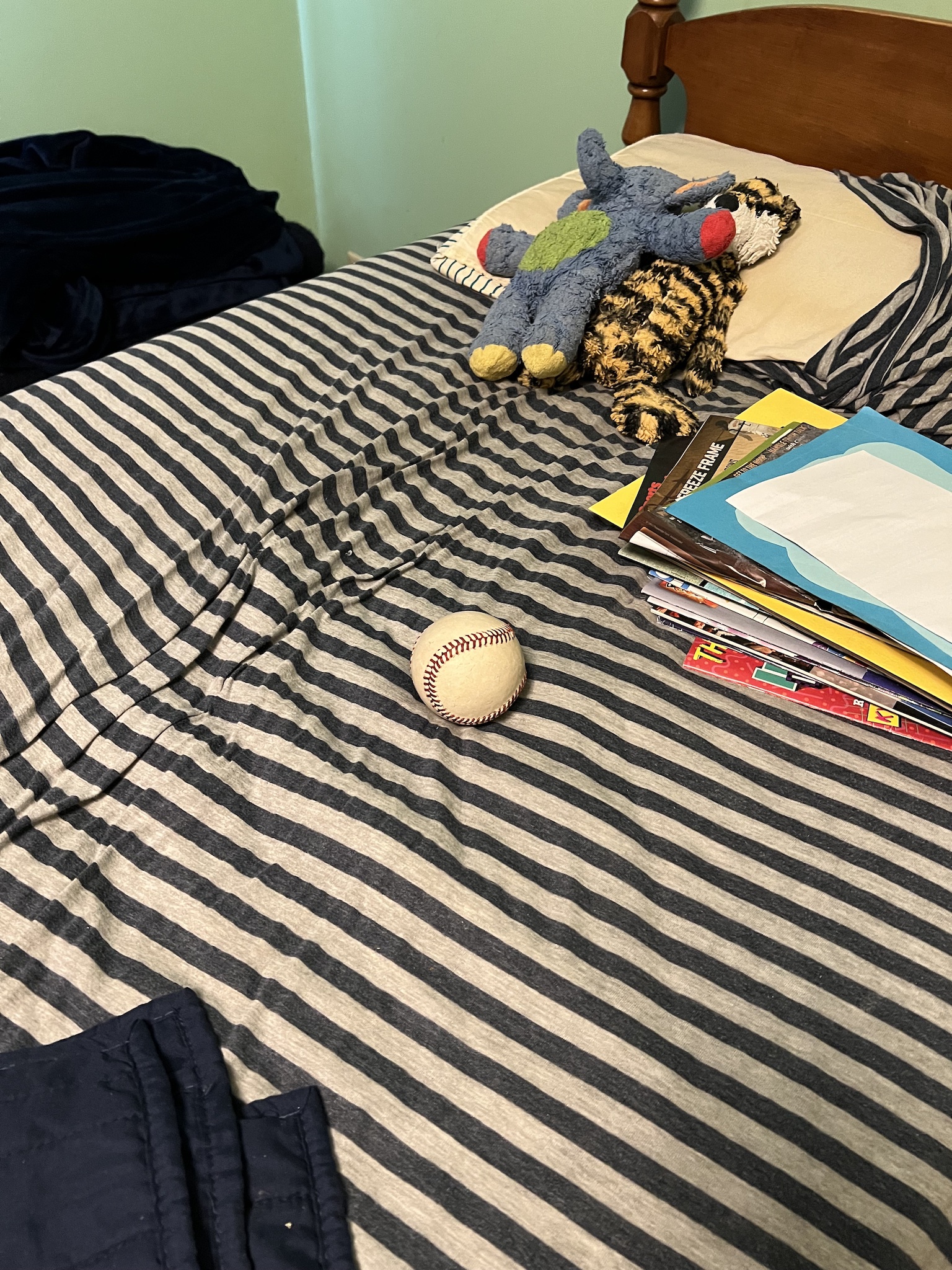 baseball and stuffed animals on messy bed