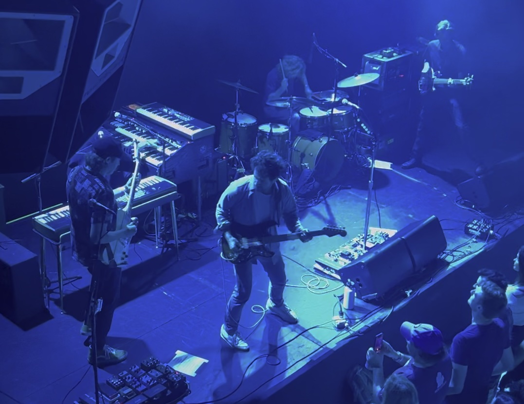 the band Dawes onstage, viewed from above in blue light