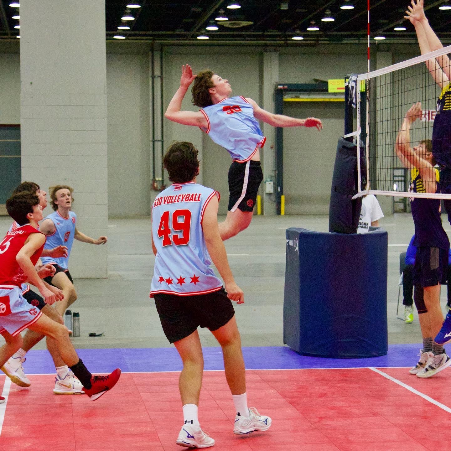 Danny in mid-air about to spike a volleyball that's above the frame